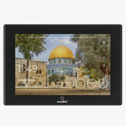 Voorzijde van een zwarte digitale adhan klok met aansluitpoorten, ventilatieopeningen en muurmontage-punten, op een witte achtergrond.